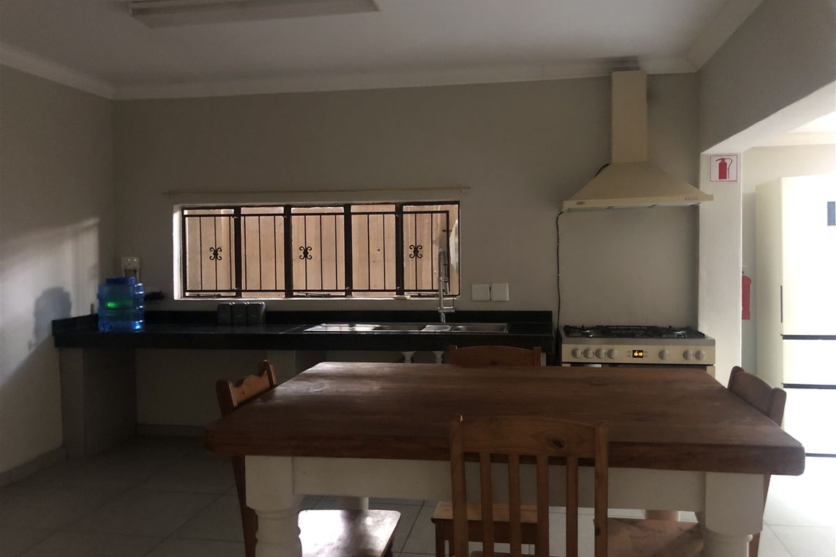 Functional kitchen featuring granite countertops, a gas hob with extractor fan, and tiled flooring, offering a practical layout for daily meal preparation.
