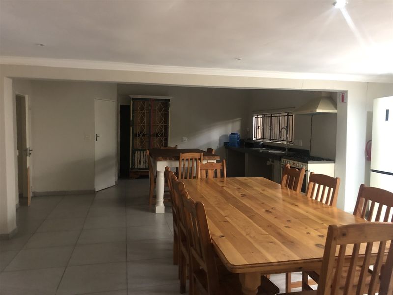 Open-plan living and dining area featuring tiled flooring, recessed lighting, and a functional kitchen space with built-in cabinetry and an extractor fan.