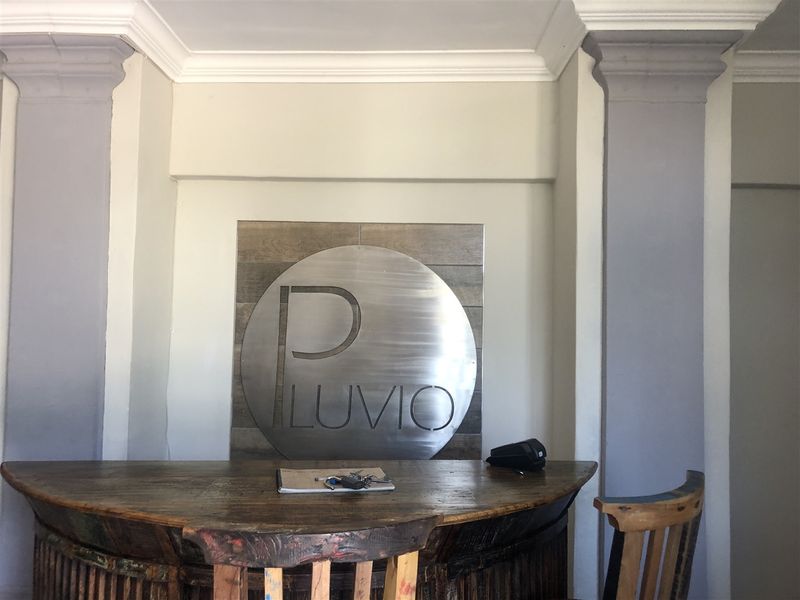 An inviting entrance area featuring decorative columns, crown molding, and a prominent feature wall with a metal logo installation.