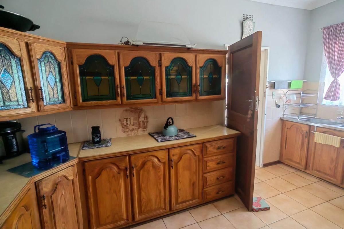 A functional kitchen featuring traditional wooden cabinetry, tiled backsplash, laminate countertops, and ceramic floor tiles, offering a classic layout with ample storage space.