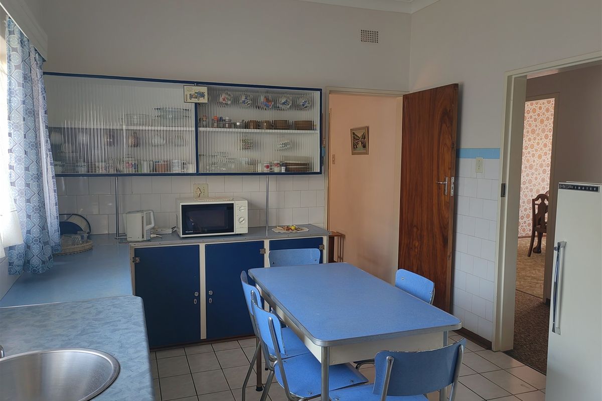 A dated kitchen featuring blue cabinetry, laminate countertops, tiled splashbacks, and tiled flooring, offering potential for a modern renovation.