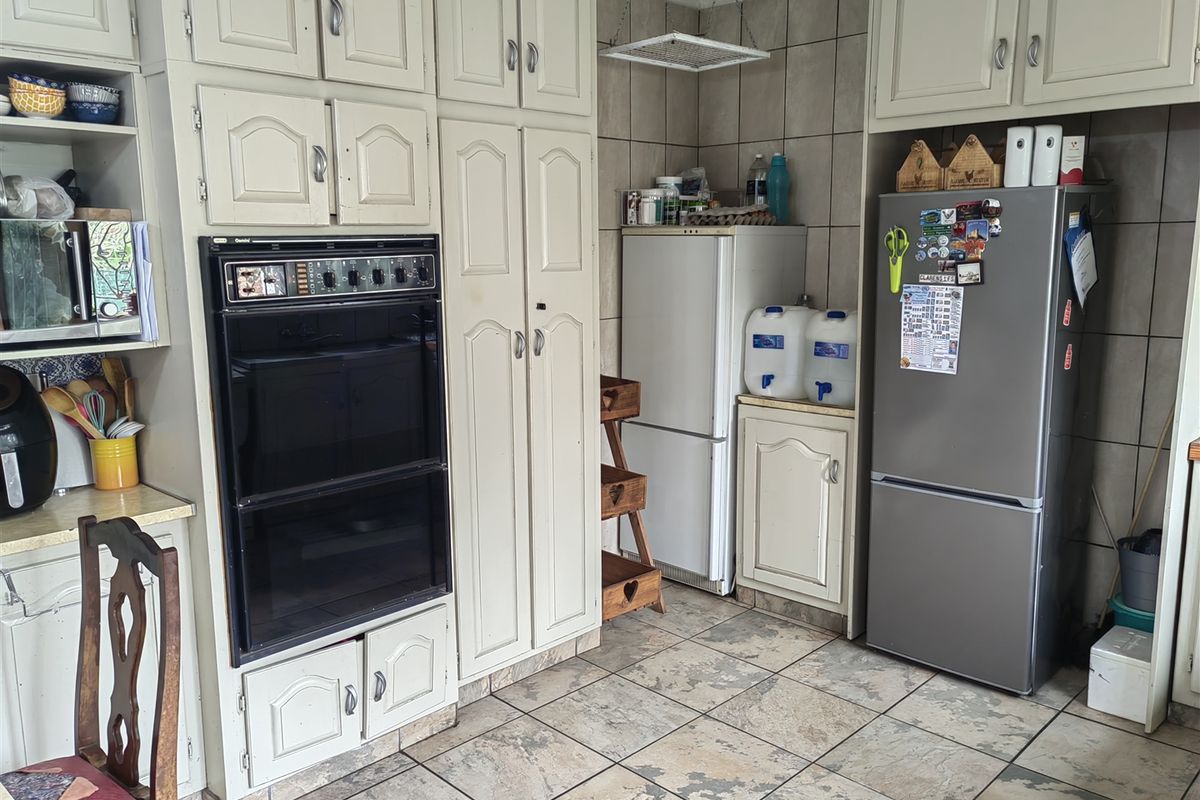 A dated kitchen featuring built-in cabinetry, a double wall oven, and tiled flooring with visible wear and tear.