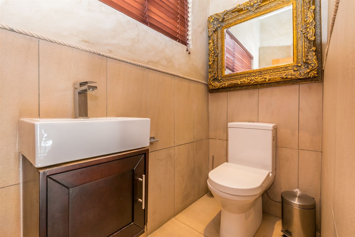 A compact, well-maintained guest bathroom featuring a modern vessel sink, vanity cabinet, and tiled finishes throughout.