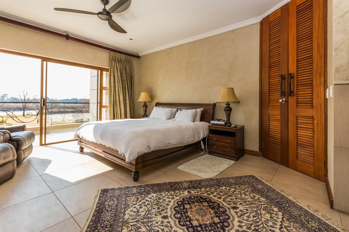 Spacious bedroom featuring tiled flooring, a ceiling fan, and louvered wooden built-in closets, with direct access to a private balcony.