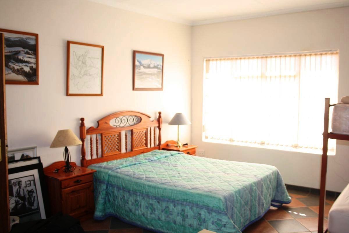 A functional bedroom featuring tiled flooring and large windows with vertical blinds, providing natural light.