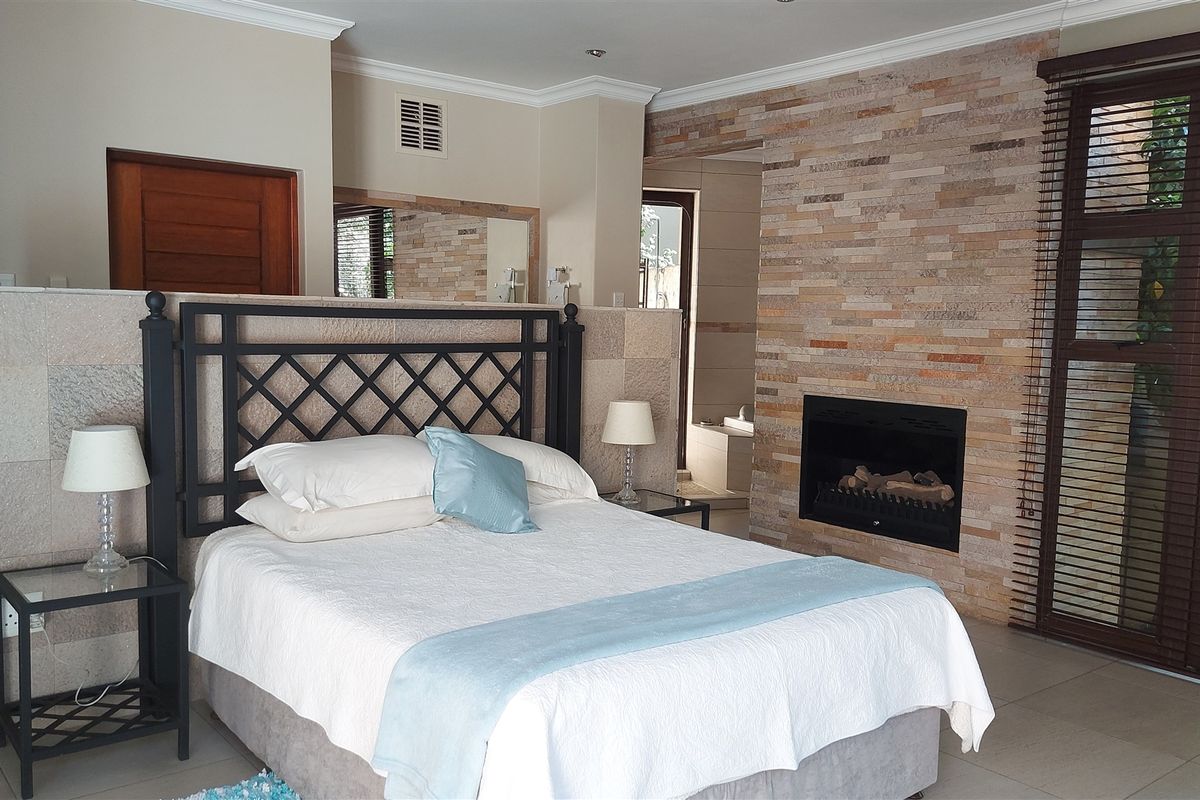 Spacious bedroom featuring a built-in stone fireplace, tiled flooring, and direct access to an outdoor area through large sliding doors.