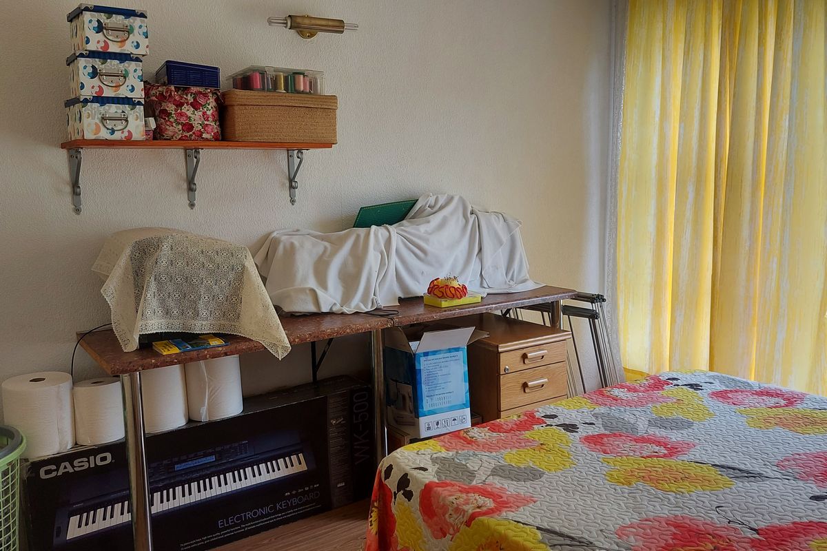 A bedroom featuring wall-mounted shelving and a sliding glass door with yellow curtains, providing natural light and access to the exterior.