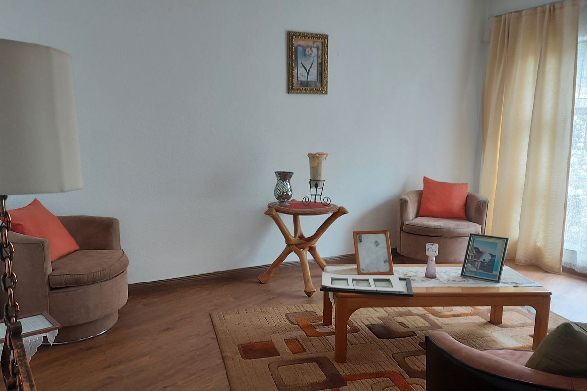 A living room area featuring laminate flooring and large windows with curtains, providing a neutral base for interior design updates.