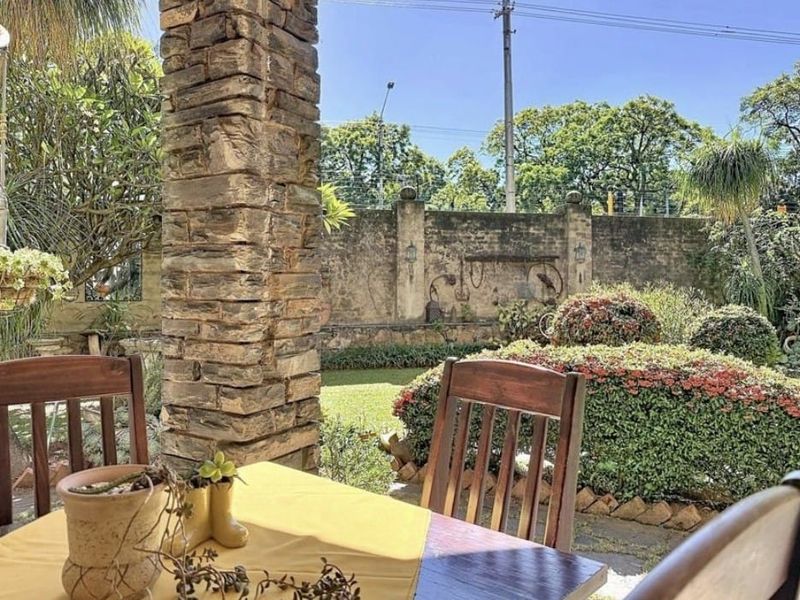 A covered patio area featuring a prominent stone-clad pillar, overlooking a landscaped garden with a secure perimeter boundary wall.
