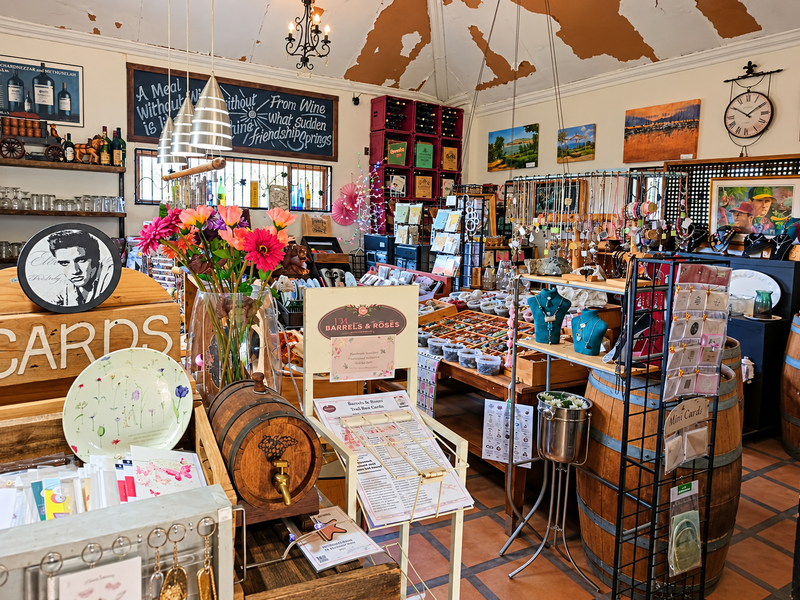 Interior view of a commercial retail space featuring vaulted ceilings, terracotta flooring, and built-in wine storage displays.