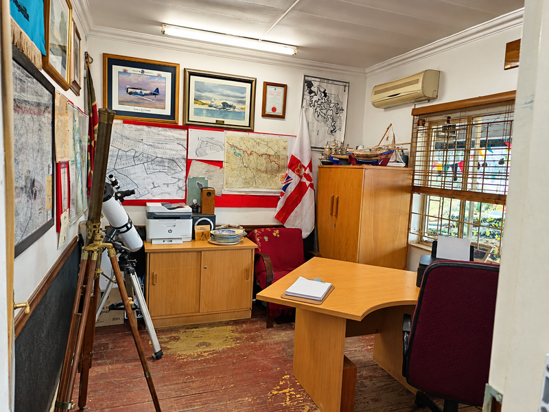 A functional office space featuring timber flooring, air conditioning, and security bars on the window, suitable for a professional or commercial workspace.