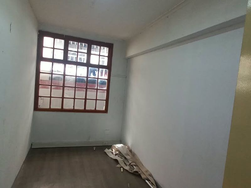 An empty office space featuring laminate flooring and a large grid-pattern window, offering a blank canvas for professional use.