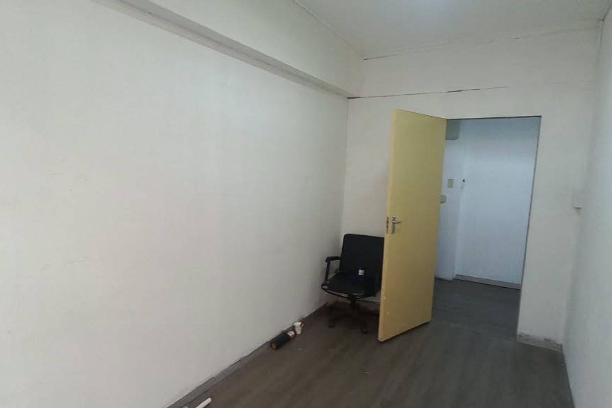 A vacant office space featuring laminate flooring and neutral walls, offering a blank canvas for professional customization.