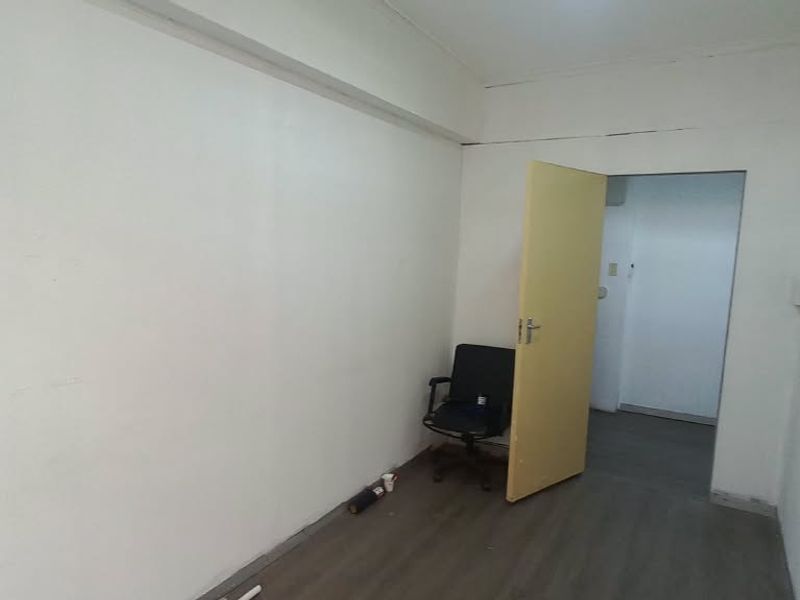 A vacant office space featuring laminate flooring and neutral walls, offering a blank canvas for professional customization.