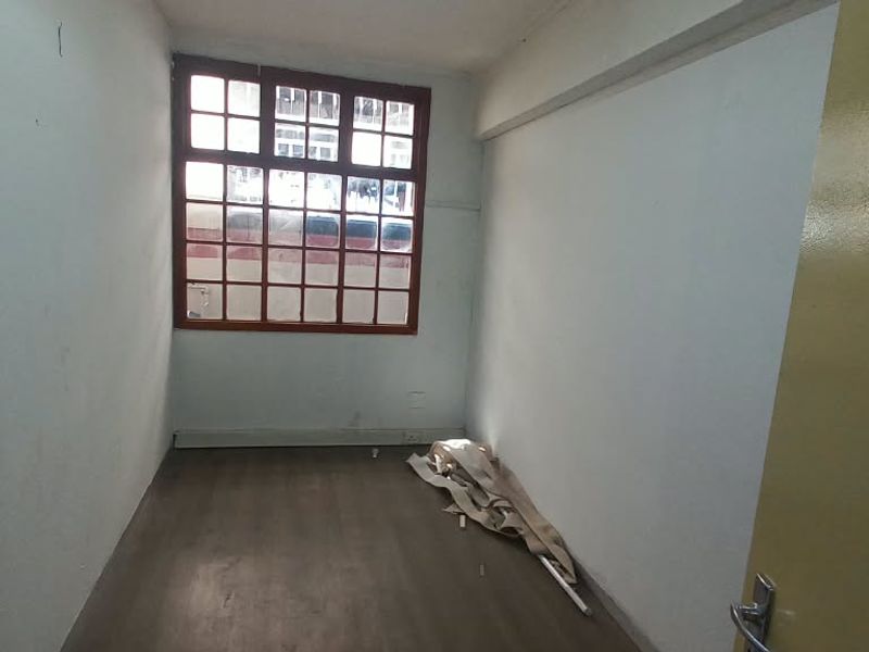 A vacant office space featuring laminate flooring and a timber-framed window, offering a blank canvas for professional workspace customization.