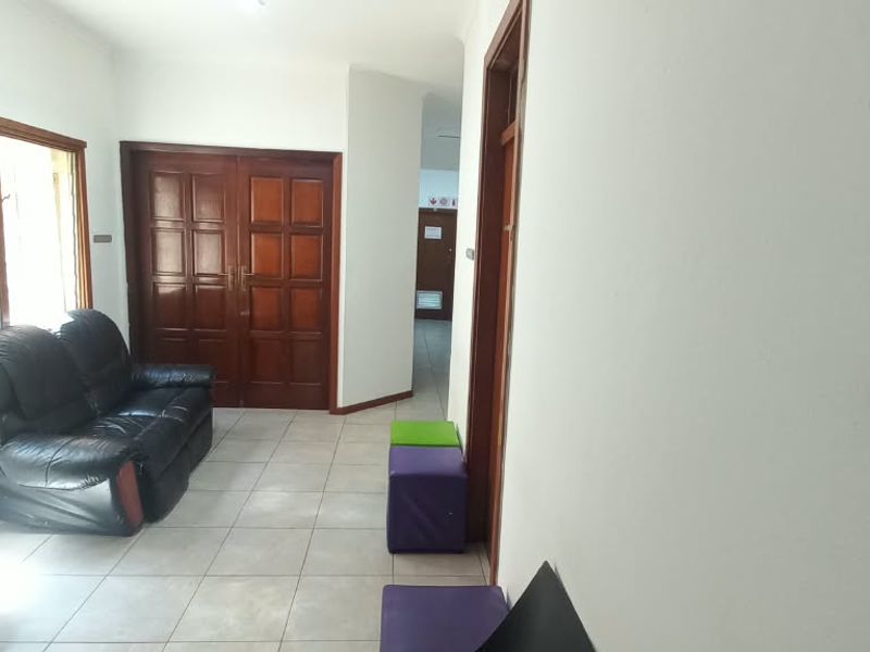 Office reception or waiting area featuring tiled flooring, wooden double doors, and natural light from large windows.