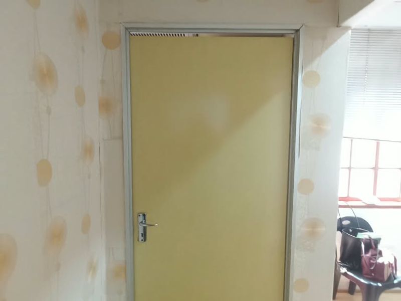 A small office space featuring patterned wallpaper, a window with blinds, and an air conditioning unit.