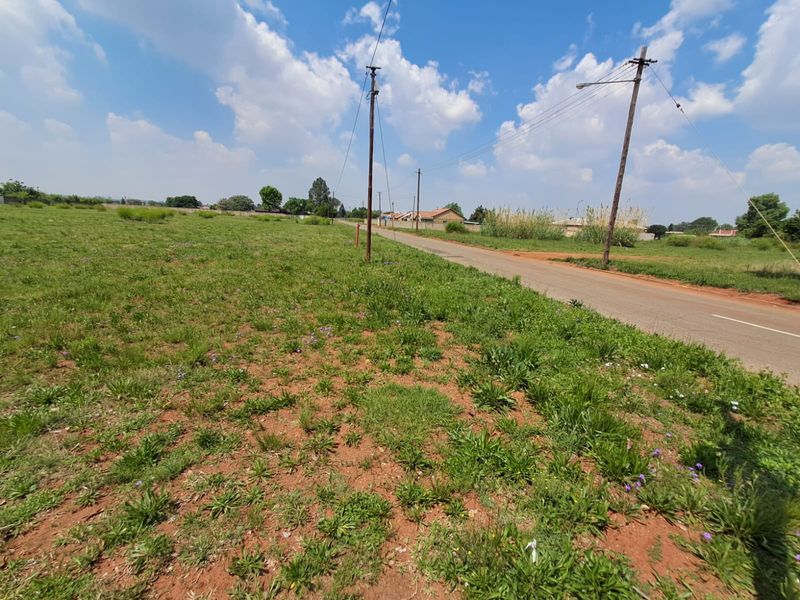 A view of the vacant commercial land parcel adjacent to a paved road with visible utility infrastructure.