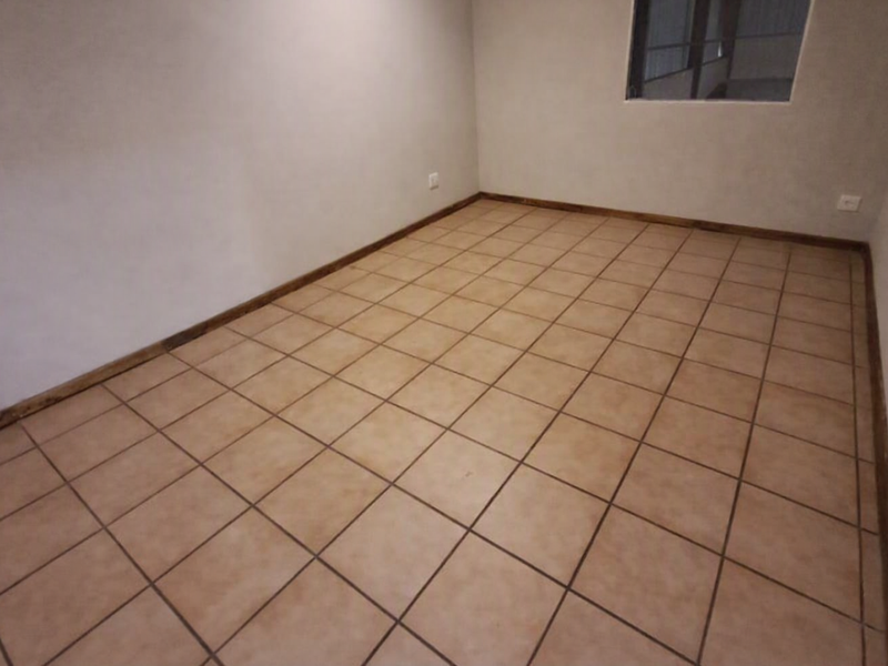 An empty, versatile room featuring neutral walls, ceramic tile flooring, and wooden skirting boards, suitable for use as an office or workspace.