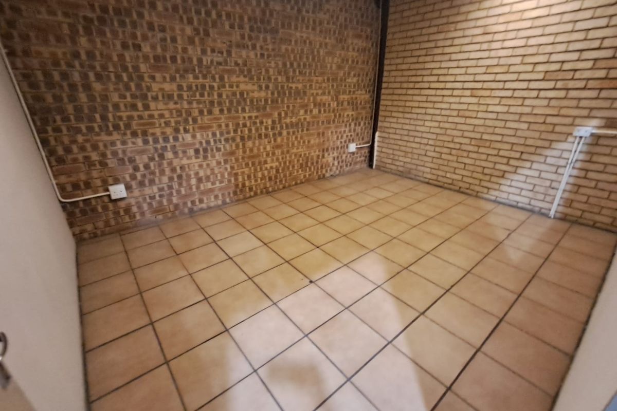 An empty utility space featuring exposed brick walls and ceramic tile flooring with surface-mounted electrical infrastructure.