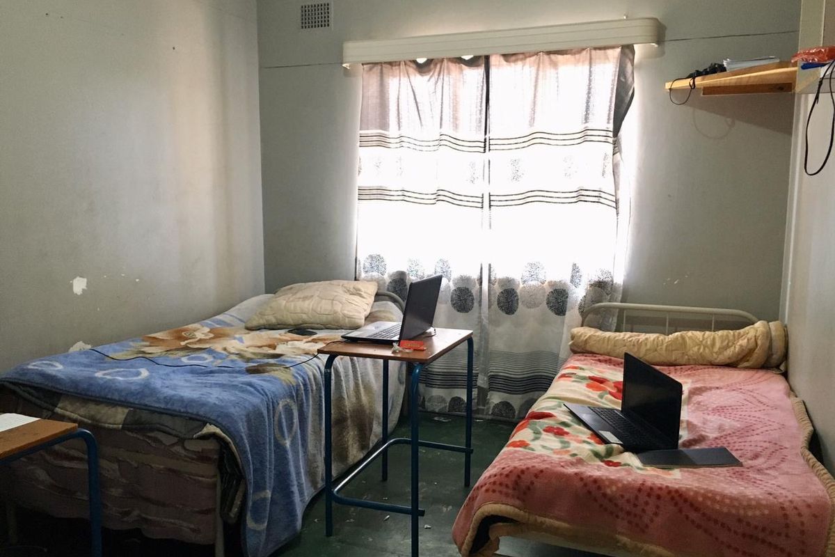 A shared bedroom featuring basic finishes, ventilation grilles, and a curtain rail. The room requires cosmetic updates to improve its overall condition.