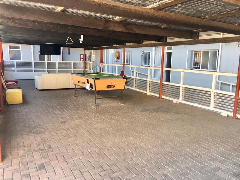 A large covered outdoor patio area featuring paved flooring, a timber roof structure, and a protective balustrade, suitable for outdoor entertainment.