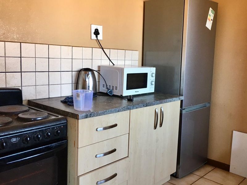 A compact kitchen area featuring built-in cabinetry, a tiled backsplash, and a freestanding stove, offering a functional layout with potential for cosmetic updates.