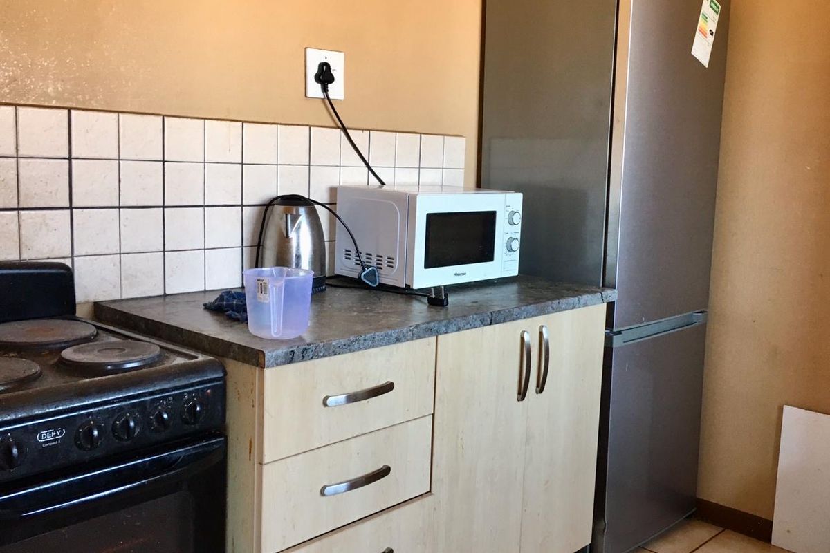 A compact kitchen area featuring built-in cabinetry, a tiled backsplash, and a freestanding stove, offering a functional layout with potential for cosmetic updates.