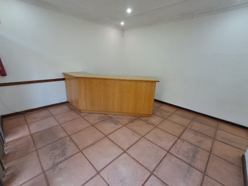 A functional office space featuring a built-in reception desk, tiled flooring, and recessed lighting, suitable for a professional workspace or reception area.
