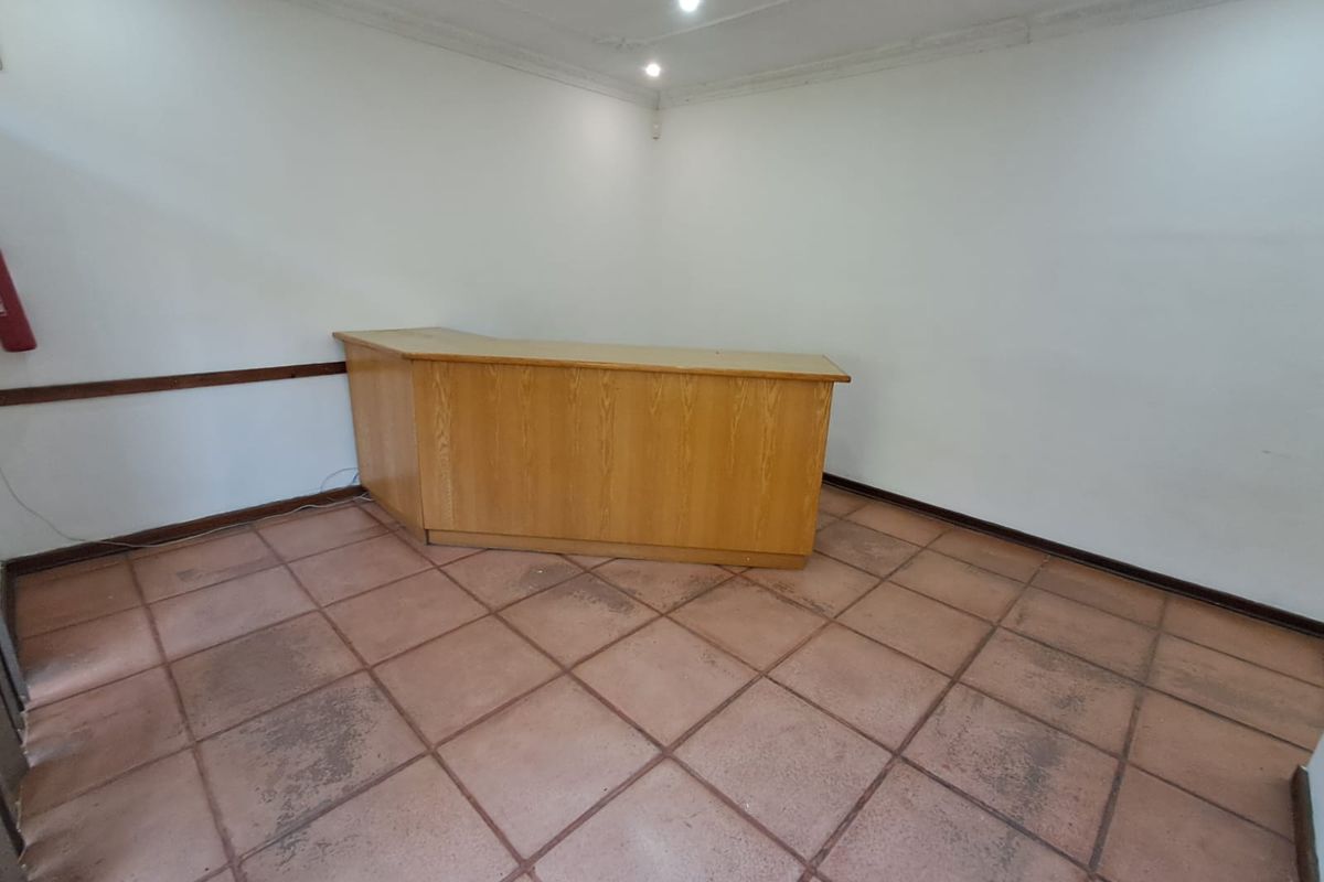 A functional office space featuring a built-in reception desk, tiled flooring, and recessed lighting, suitable for a professional workspace or reception area.