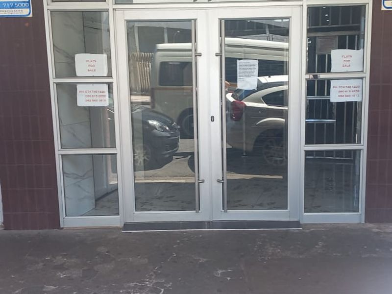 Front entrance of a retail property featuring aluminium-framed glass double doors and tiled exterior wall finishes.