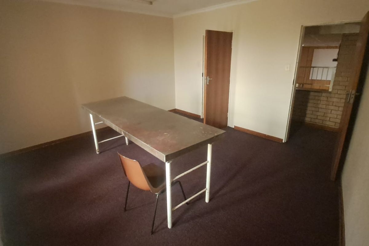 A sparsely furnished room featuring dark carpeting, neutral walls, and two doorways leading to adjacent spaces.