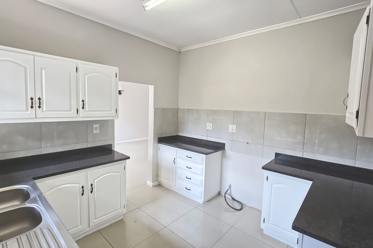 A functional kitchen space featuring white cabinetry, dark countertops, and a double stainless steel sink, ready for appliance installation.