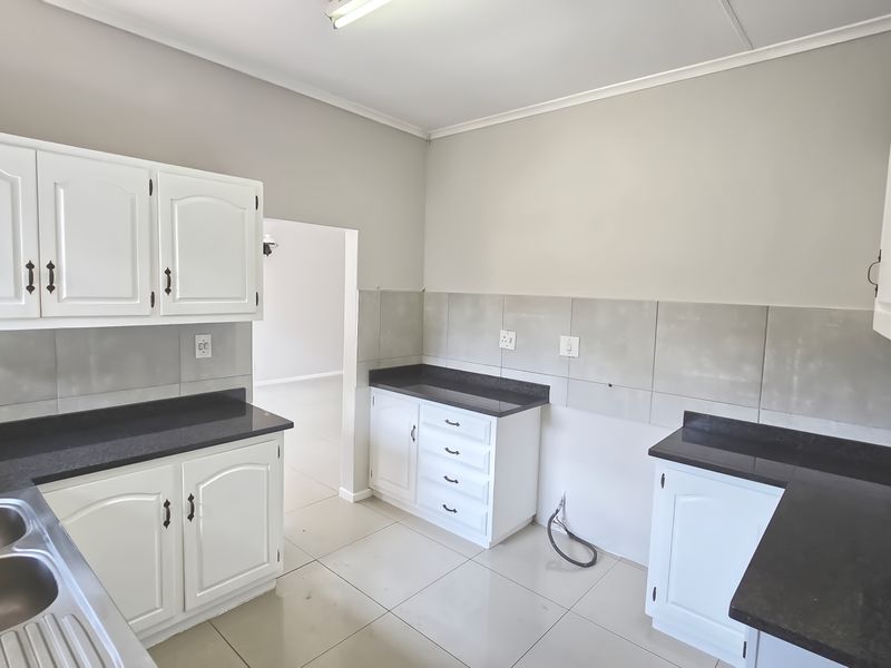 A functional kitchen space featuring white cabinetry, dark countertops, and a double stainless steel sink, ready for appliance installation.