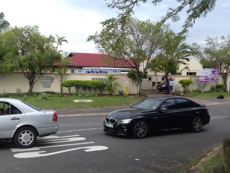 Street view of the property showing the boundary wall, gated entrance, and tiled roof structure from the road.