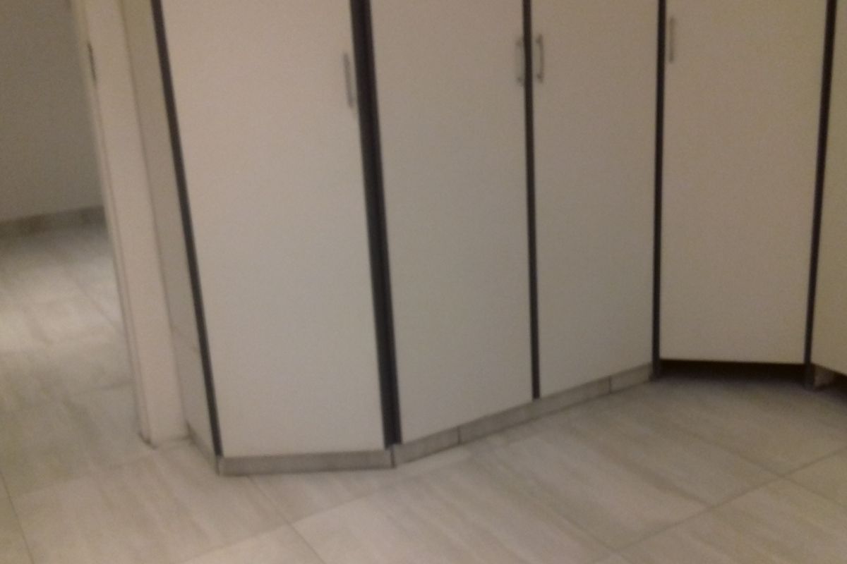 A bedroom interior featuring built-in cupboards and light-toned tiled flooring.