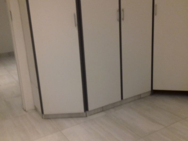 A bedroom interior featuring built-in cupboards and light-toned tiled flooring.