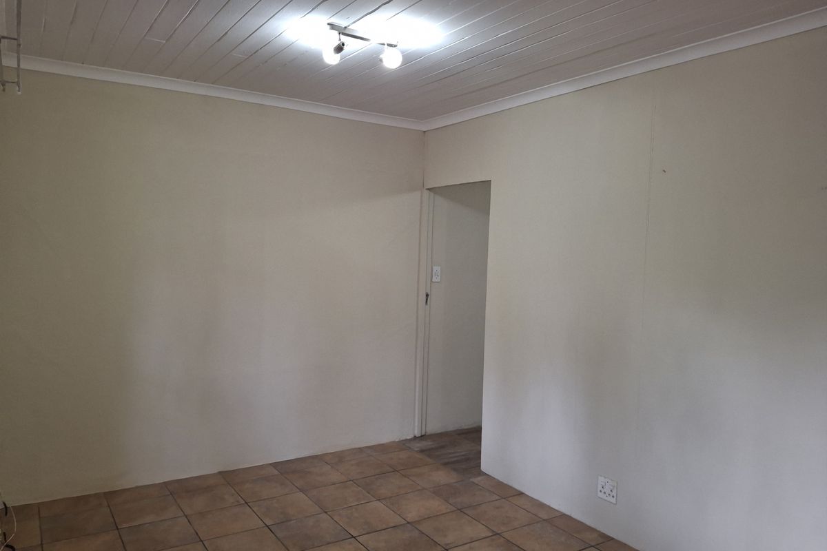 An empty living room featuring tiled flooring, a white timber tongue and groove ceiling, and neutral wall finishes.
