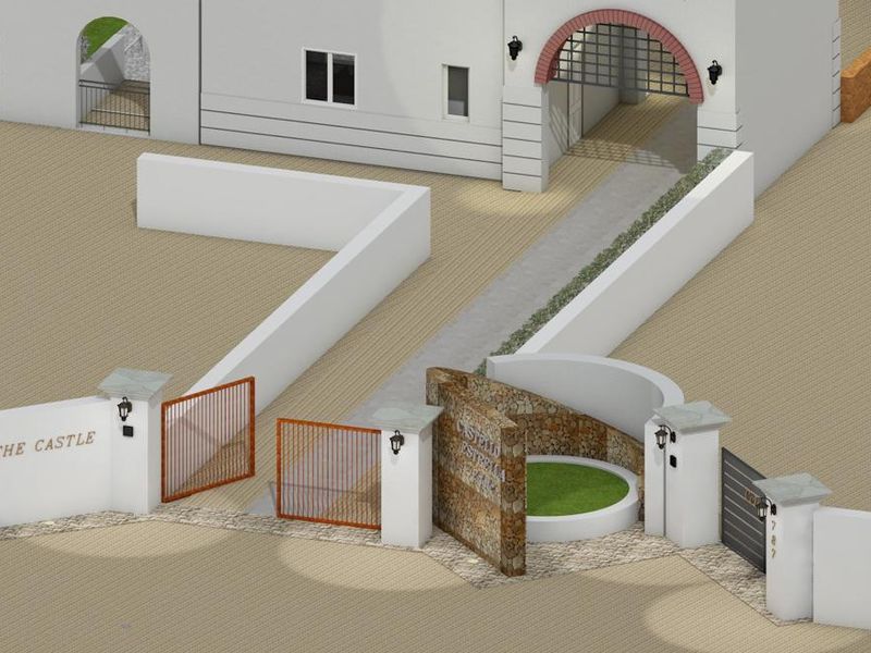 An elevated view of the property entrance featuring a stone feature wall, metal gates, and a paved driveway leading to an arched entryway.