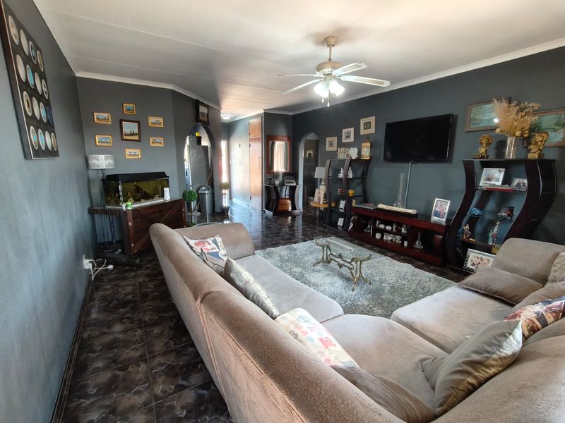 A spacious living room featuring dark tiled flooring, a ceiling fan, and distinctive archways leading to adjacent areas.