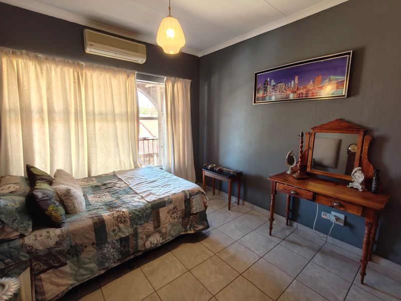 A bedroom featuring tiled flooring, a split-system air conditioner, and access to a balcony through a sliding door.