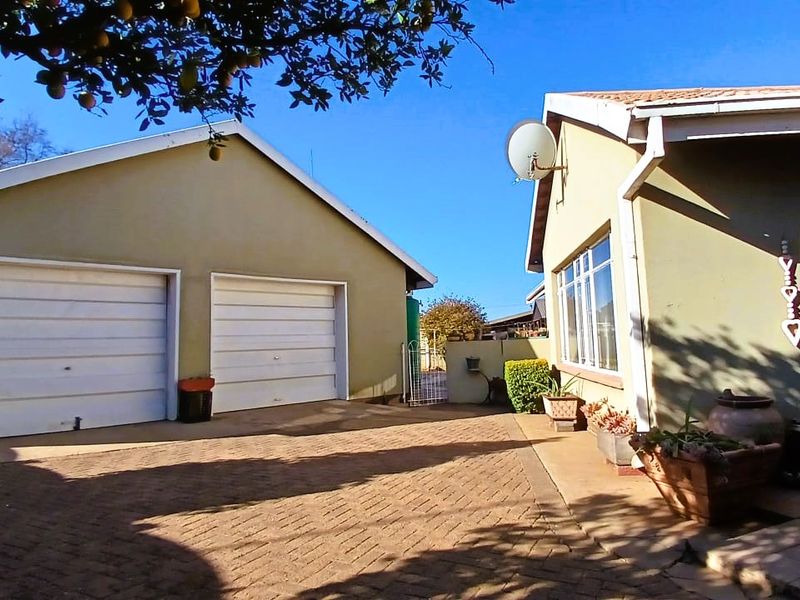 Front exterior view of the property featuring a double garage with white roll-up doors and a paved driveway area.
