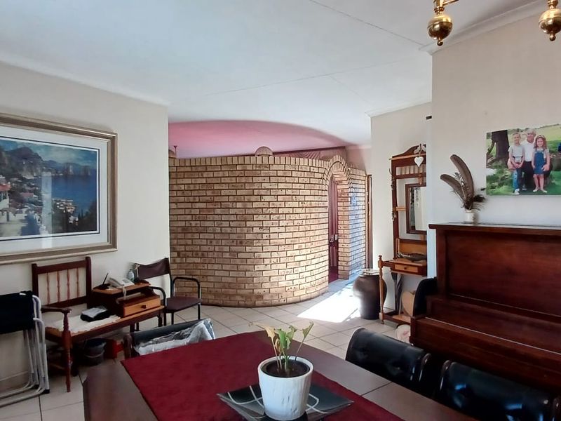 Living area featuring a distinctive curved face-brick feature wall and archway, with neutral tiled flooring throughout the space.