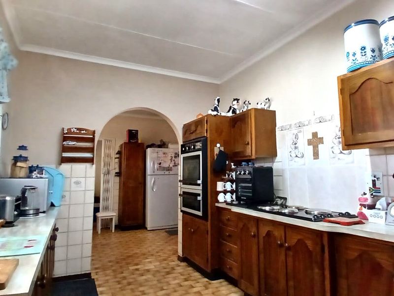 A functional kitchen featuring traditional wooden cabinetry, a built-in double oven, and a tiled backsplash, leading through an archway to an adjacent area.