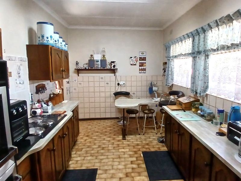 A dated kitchen featuring traditional wooden cabinetry, laminate countertops, a built-in oven, and tiled backsplash, offering significant potential for modern renovation.