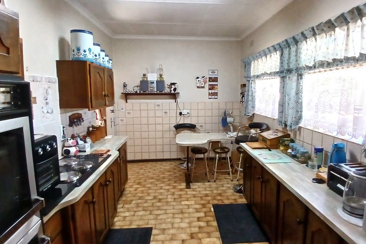A dated kitchen featuring traditional wooden cabinetry, laminate countertops, a built-in oven, and tiled backsplash, offering significant potential for modern renovation.