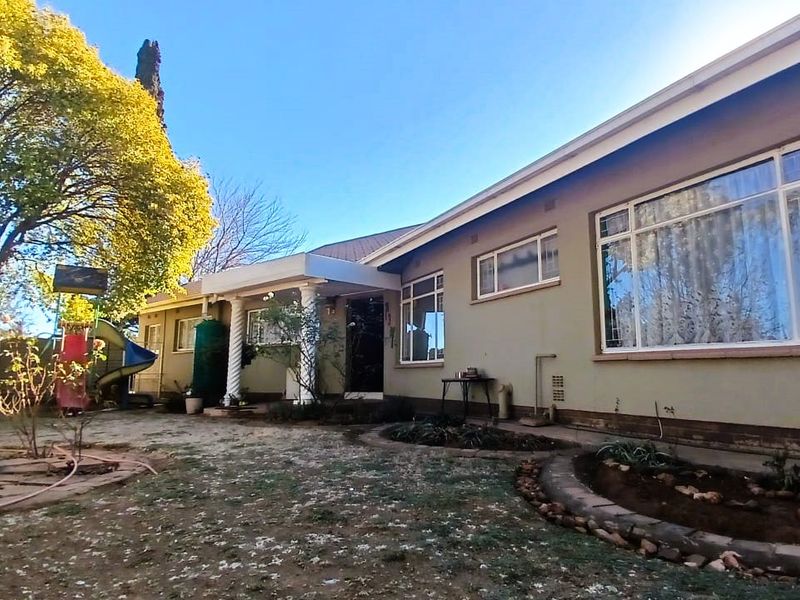 Rear view of the house featuring a covered patio area, decorative columns, and large windows overlooking the garden.