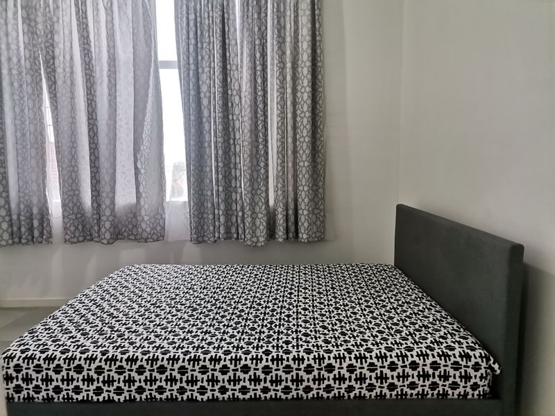 A simple bedroom featuring neutral walls and a window with curtains.