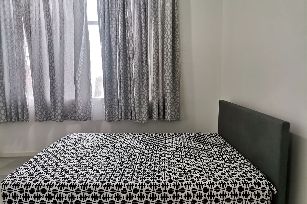 A simple bedroom featuring neutral walls and a window with curtains.