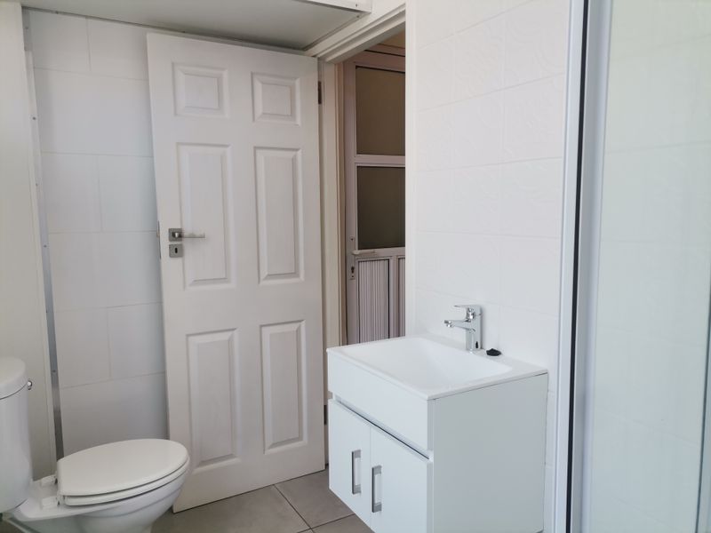 A clean, modern bathroom featuring a white vanity with basin, toilet, and tiled finishes, presenting a bright and functional space.